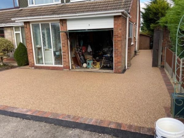 Gold resin driveway with paving border in Brockworth